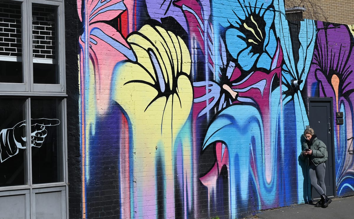 Person by wall decorated with street art.